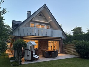 A two-story house with a balcony, a patio with outdoor furniture, and a brick exterior. - Starklef 34a, Whg. 2, Huus Starklef - Komfort Ferienwhg. in Wyk, 4 Personen, OG in 2- Familienhaus, (Wyk auf Föhr)