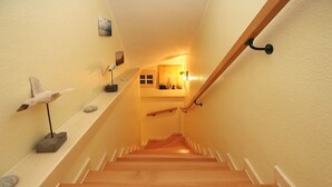 Un escalier en bois avec des rampes blanches, une sculpture d’oiseau et une petite étagère ornée d’objets décoratifs.