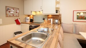 A kitchen with white cabinets, a stainless steel sink, a coffee maker, and a toaster. - Ohl Dörp 22 Pastoratshof, Haus 3 - Ferienwohnung in Wrixum, mit 3- Zimmern auf 60m² im Reetdachhaus (Wrixum)
