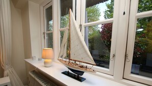 A model sailboat on a windowsill, a lamp, and a radiator. - Ohl Dörp 22 Pastoratshof, Haus 3 - Ferienwohnung in Wrixum, mit 3- Zimmern auf 60m² im Reetdachhaus (Wrixum)