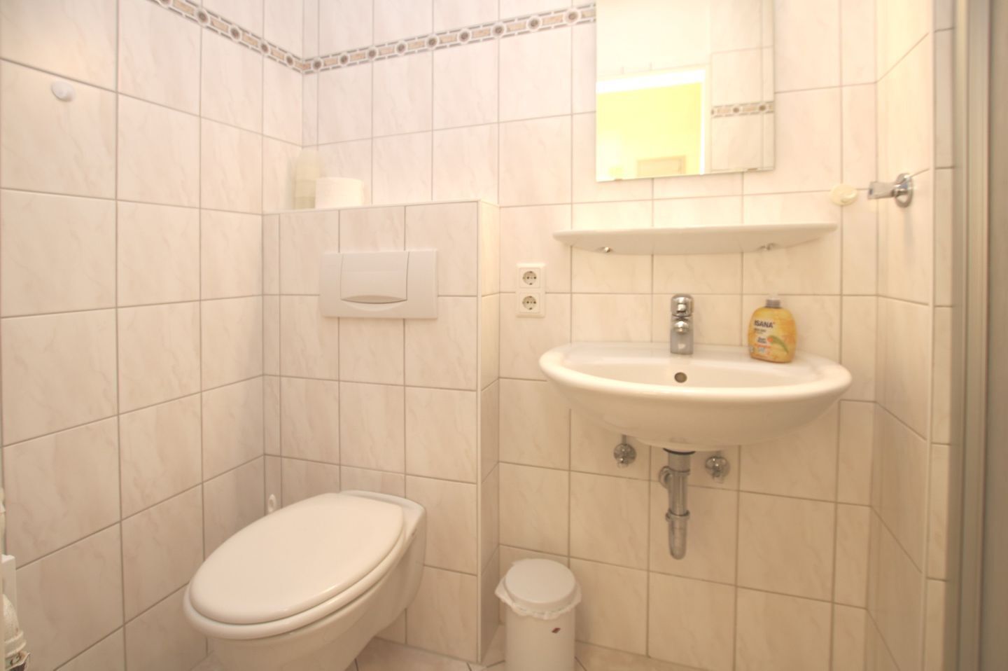 A small bathroom with a toilet, sink, and mirror.