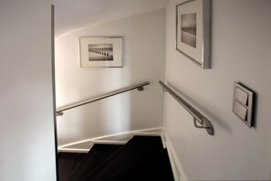 A stairway with handrails, a door, and two framed pictures on the walls. - Lüttmarsch 13, Whg. 1 - Apartment with 2 rooms on approx. 55m² (Wyk auf Föhr)