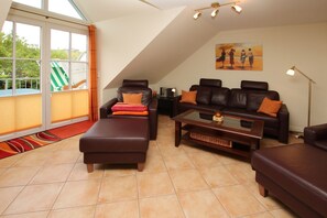 A spacious living area with a large window, a sofa, a recliner, and a coffee table. - Wiesenweg 4, Whg. 4, Druummeere - Holiday apartment with 3 rooms on approx. 100 m² (Wyk auf Föhr)