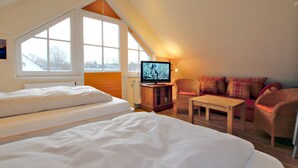 A bedroom with a large bed, a television, a small table, and a sofa. - Wiesenweg 4, Whg. 4, Druummeere - Holiday apartment with 3 rooms on approx. 100 m² (Wyk auf Föhr)