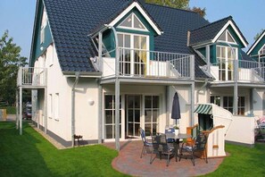 A two-story house with a balcony, a patio with outdoor furniture, and a small garden area. - Wiesenweg 2a, Whg. 3, Ruusfeen - vacation apartment with 3 rooms over approx. 100m² in the (Wyk auf Föhr)