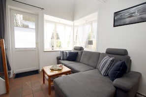 A living room with a grey sofa, a wooden coffee table, and a painting on the wall.
