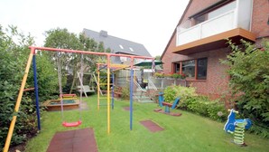 A backyard with a swing set, climbing frame, and a small play area. - Berliner Ring 24, Whg. 1 "Max" - vacation apartment in a 3-family house, approx. 95m², 3 (Wyk auf Föhr)