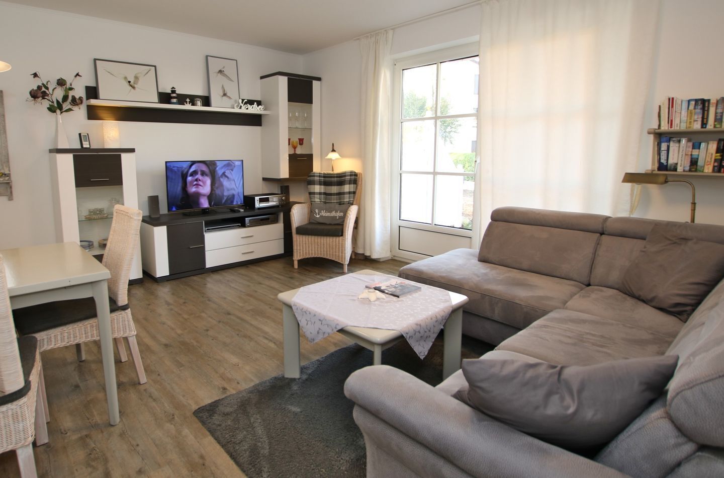 A modern living room with a sofa, a dining table, a TV, and a bookshelf.