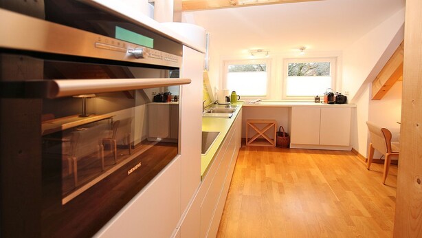 Une cuisine moderne équipée d’un four encastré, d’un évier et d’une fenêtre donnant sur un jardin.