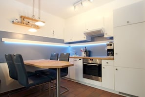 Una cucina moderna con tavolo da pranzo, sedie, forno a incasso e macchina da caffè.