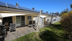 Een rij vakantiehuisjes met zonnepanelen, een overdekt terras en een houten terras.
