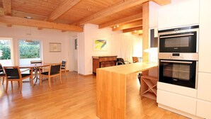 A modern kitchen with wooden flooring, a central island, and built-in ovens. - Am Grünstreifen 29, Haus Liguster Whg. no. 1 - vacation apartment in 2-family house, approx. (Wyk auf Föhr)
