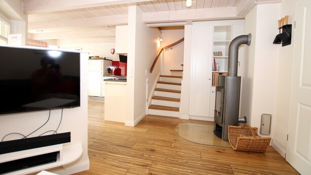 Eine moderne Küche mit Holzboden, einem integrierten Fernseher und einer Treppe, die zu einem Erkerraum führt.