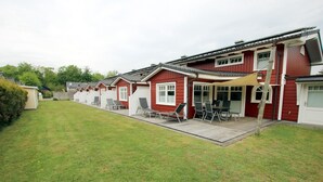 Eine Reihe von roten Mobilheimen mit Anbauten und Terrassen, jedes mit Tisch und Stühlen.