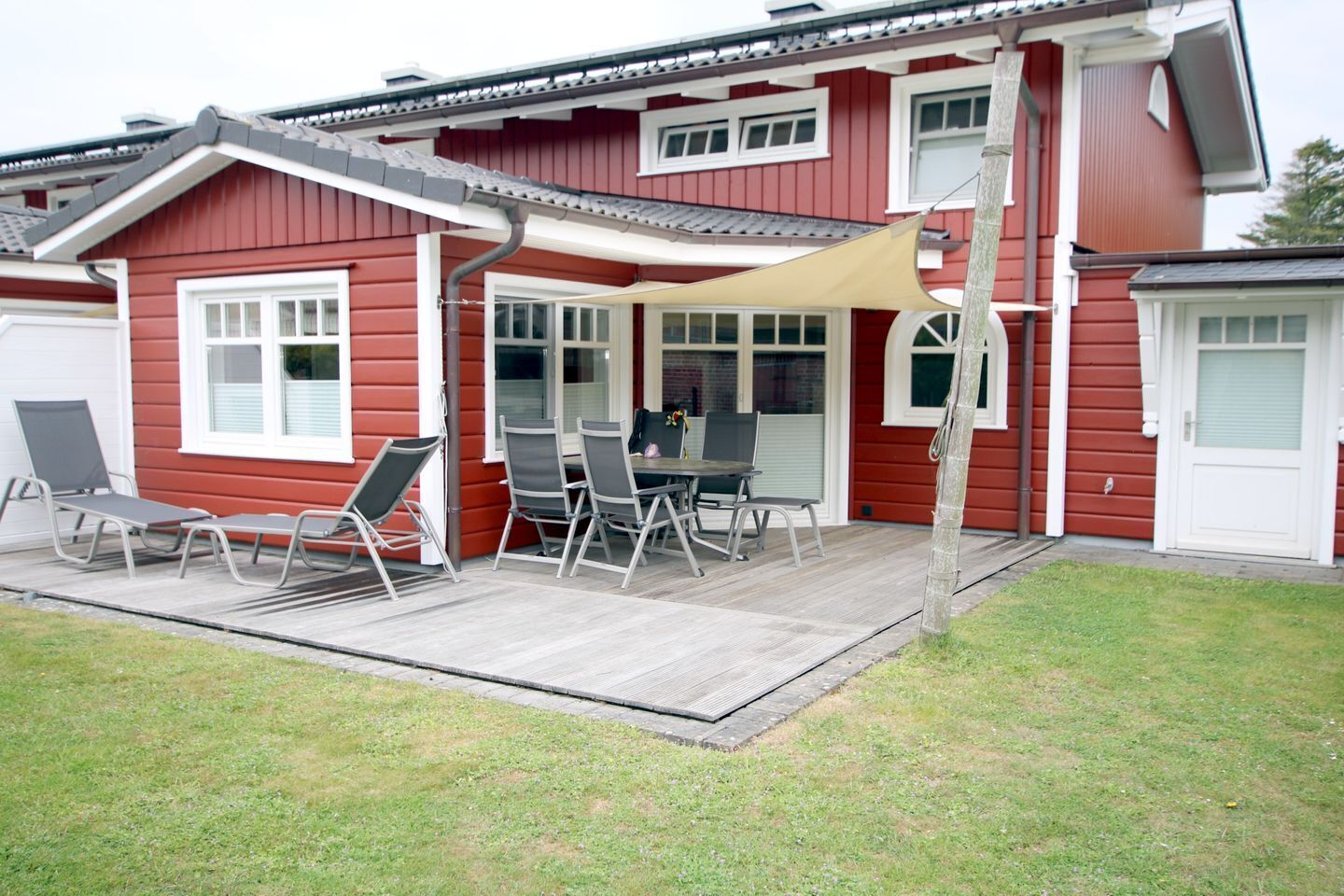 Ein rotes Haus mit einer Veranda, einem Tisch und vier Stühlen.