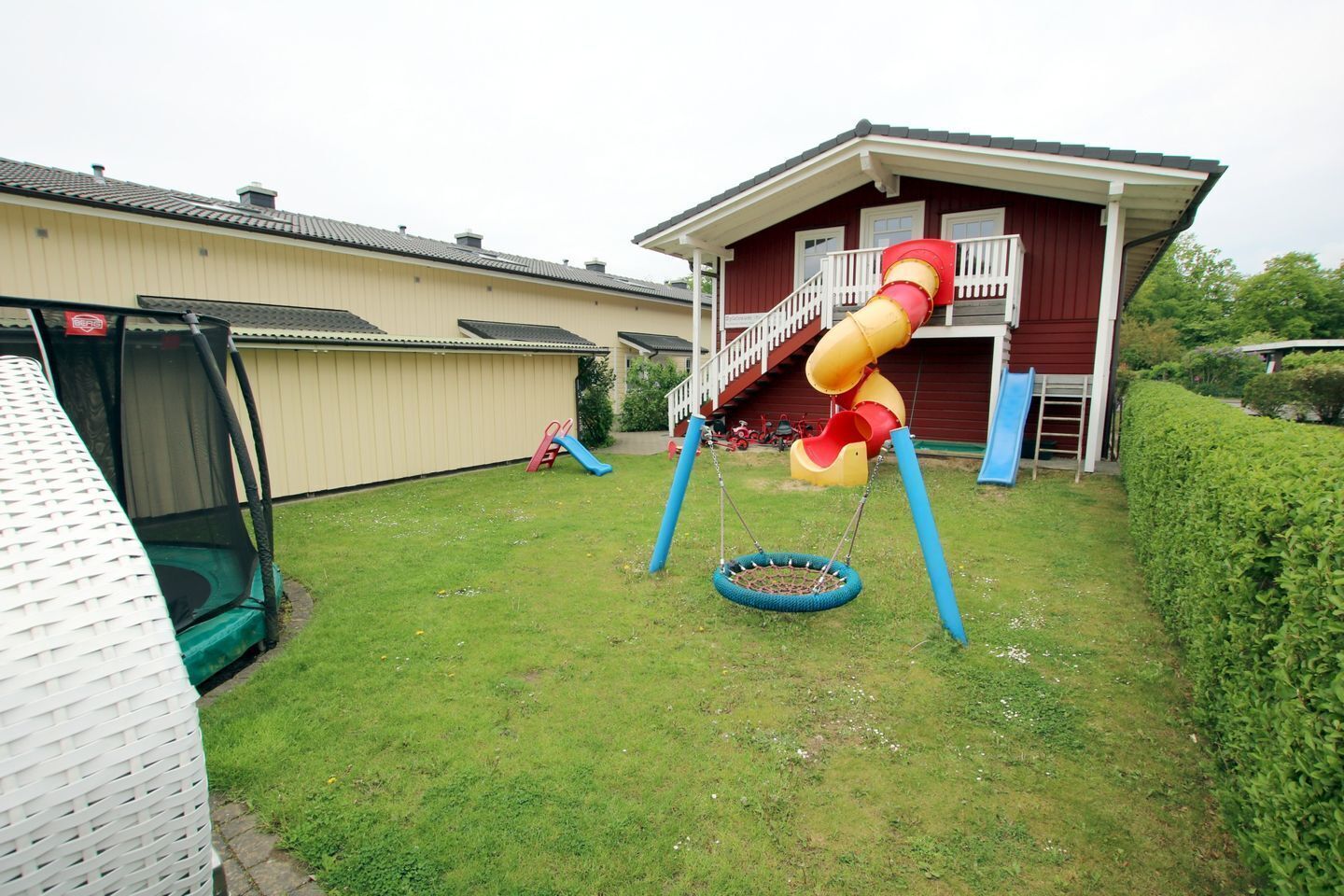 Un giardino con altalene, scivolo e trampolino.
