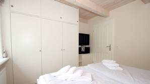 A bedroom with a bed, a wardrobe, and a television. - Haus Seehund, Susanne-Fischer Weg 15 - 5 star vacation home with approx. 98 sqm (Wyk auf Föhr)