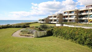 Un hotel frente al mar con varios balcones, un jardín ajardinado y vistas al océano.