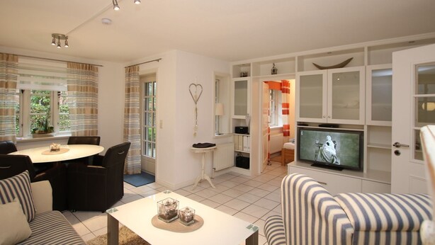 A living room with a dining area, a television, and a heart-shaped decoration on the wall. - Rungholtstraße 3c, Whg. 2 - Ferienwohnung mit 3- Zimmern auf ca. 65m² (Wyk auf Föhr)