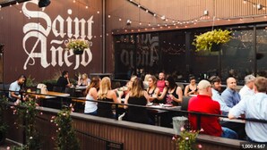 An outdoor dining area with tables and chairs, a large sign reading "Saint Anejos", and hanging plants. - UPSCALE Cozy Nashville Condo★ POOL, PATIO, PARKING (Nashville)
