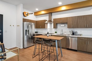 A modern kitchen with stainless steel appliances, wooden cabinets, and a bar stool area.