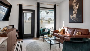 A modern living room with a leather sofa, a glass coffee table, and a green armchair. - UPSCALE Cozy Nashville Condo★ POOL, PATIO, PARKING (Nashville)