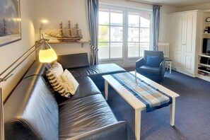 A modern living room with a sofa, armchair, and a coffee table. - Gmelinstraße 12, Whg. 18, Haus Meeresbrandung - Ferienwohnung mit 2-zimmern mit ca. 45m² und Balkon (Wyk auf Föhr)