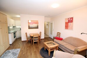 A compact living space with a kitchenette, a dining area with a table and chairs, a sofa, and a small coffee table. - Gmelinstraße 12, Whg. 4, Haus Meeresbrandung - Holiday apartment with 2 rooms on (Wyk auf Föhr)