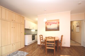 A compact kitchen with wooden cabinets, a dining table with chairs, and a pendant light. - Gmelinstraße 12, Whg. 4, Haus Meeresbrandung - Holiday apartment with 2 rooms on (Wyk auf Föhr)