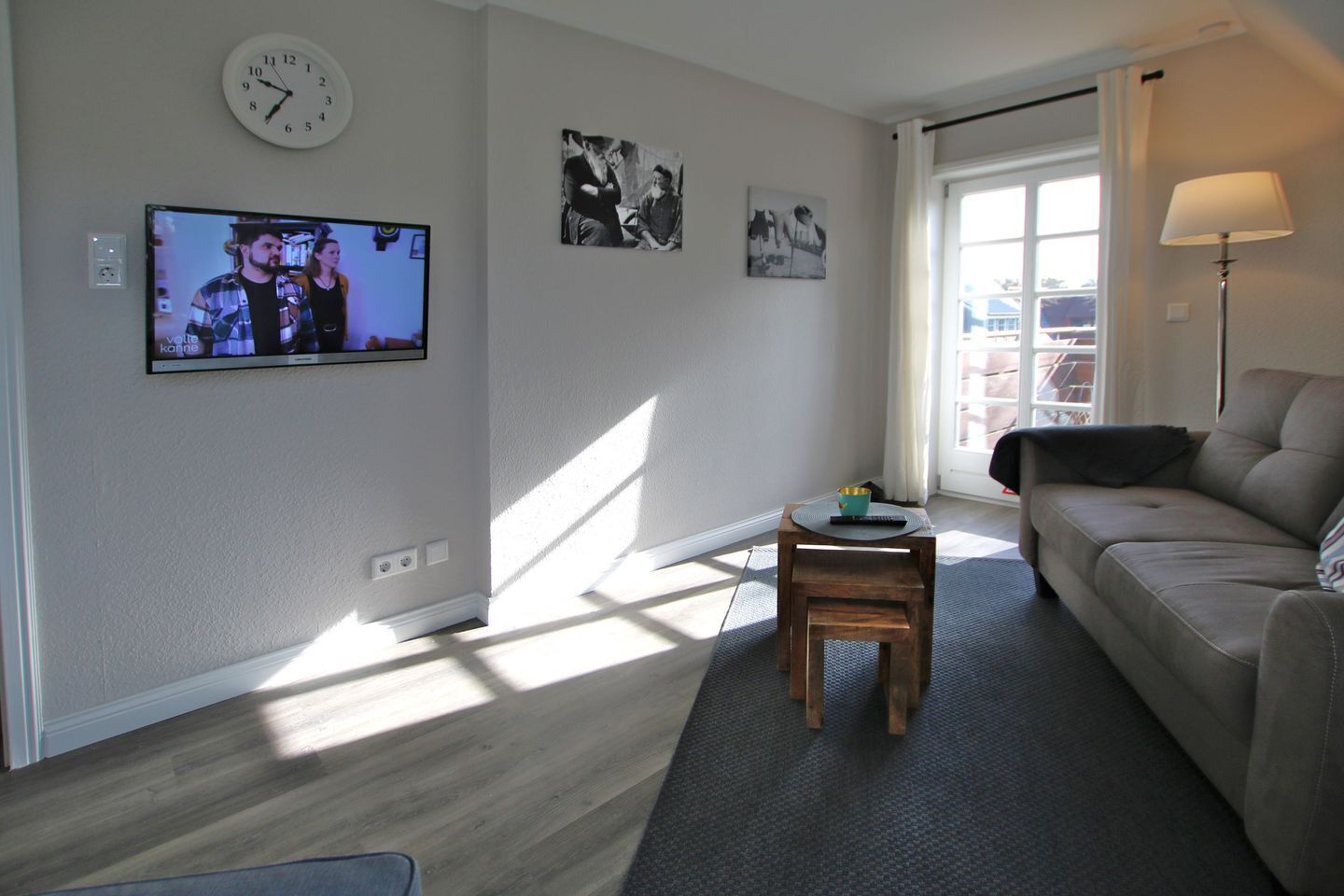 Un salon avec un canapé, une table basse, un téléviseur et une horloge au mur.