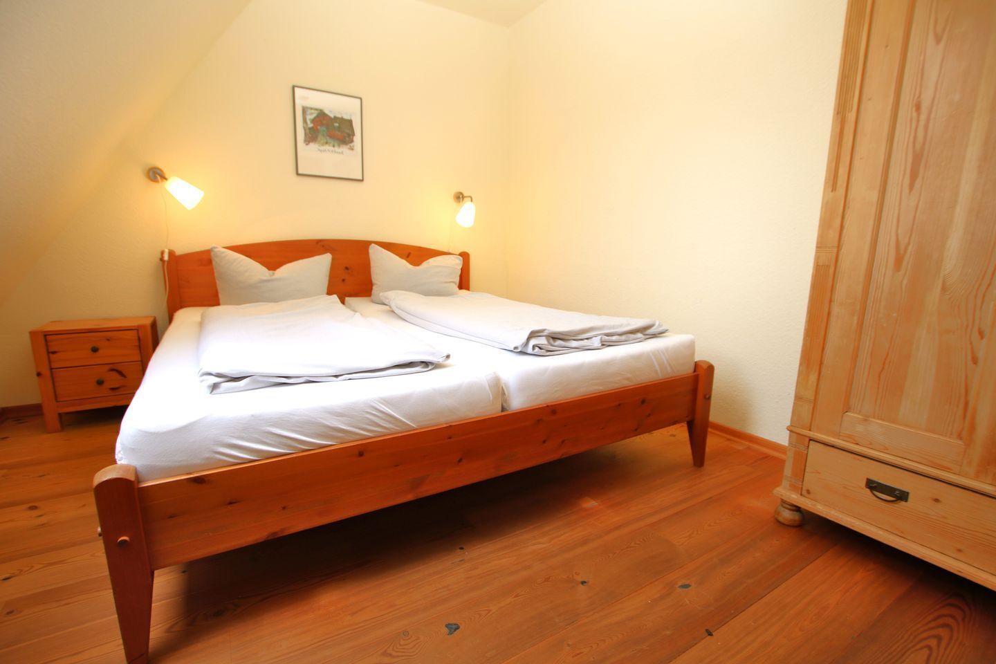 A single bed with white linens, a wooden headboard, two bedside tables, and a wardrobe.