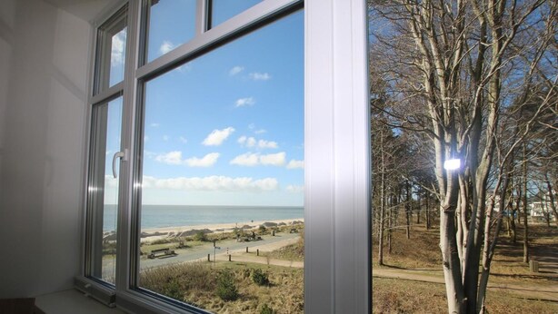 A window with a view of a beach, trees, and a clear sky. - Stockmannsweg 14, Whg.4 Haus am Meer - Ferienwohnung mit 3- Zimmern, ca. 80m² im 1. OG mit Blick auf (Wyk auf Föhr)