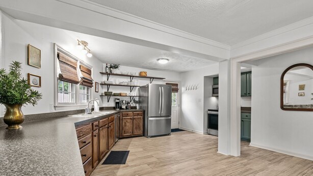 A modern kitchen with wooden cabinets, a stainless steel refrigerator, and a granite countertop.