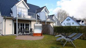 Ein zweistöckiges Haus mit Balkon, einer Terrasse und Gartenmöbeln sowie einer Solaranlage.