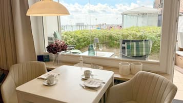 Ein Essbereich mit Tisch für zwei Personen, einem Blumenstrauß und Blick auf das Meer und einen Steg.