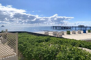 Une plage avec une jetée, des chaises longues et une clôture.