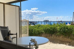 Une terrasse avec une table et des chaises, donnant sur une jetée et la mer.