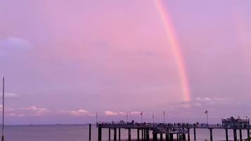 Eine Pier, die sich über ein Gewässer erstreckt, mit einem Regenbogen am Himmel.