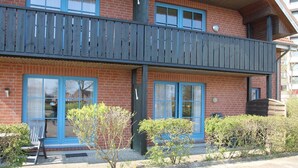 Un bâtiment en briques de deux étages, doté de fenêtres à cadre bleu et d’un balcon en bois.