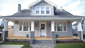 A two-story house with a front porch, a central door, and a chimney. - Charming Remodeled 4 Bedroom Home in Downtown High Point (High Point)