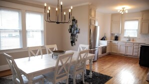 A modern kitchen with white cabinetry, a dining table with chairs, and a chandelier. - Charming Remodeled 4 Bedroom Home in Downtown High Point (High Point)