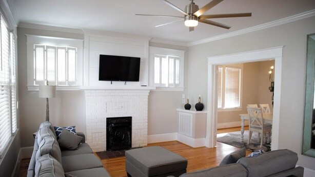 A living room with a fireplace, a sofa, a television, and a ceiling fan. - Charming Remodeled 4 Bedroom Home in Downtown High Point (High Point)