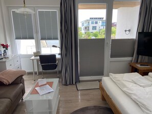 Ein modernes Hotelzimmer mit einer Couch, einem Schreibtisch, einem Sessel, einem Bett und einem Fernseher.