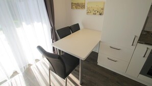 Una cocina moderna con una mesa y sillas blancas, suelo de madera y un armario con cajones.