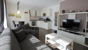 Una sala de estar moderna con un sofá gris, un televisor de pantalla plana y una mesa de centro blanca.