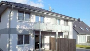 A two-story house with a balcony, a fenced backyard, and a clear sky. - 1010 - Seesternweg - OG - 1010 / Seesternweg in Dahme (Dahme)