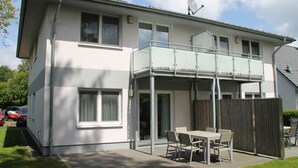 A two-story house with a balcony, a fenced patio, and a car parked in the driveway. - 1010 - Seesternweg - OG - 1010 / Seesternweg in Dahme (Dahme)