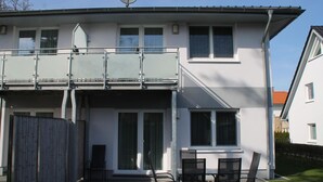 A two-story house with a balcony, a sliding glass door, and a patio with chairs. - 1012 - Holiday apartment Strandburg - 1012 Holiday apartment Strandburg (Dahme)