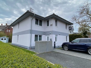 Un immeuble résidentiel à deux étages, doté d’un design moderne, avec un toit plat, de grandes fenêtres et un garage apparent.