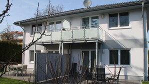 A two-story house with a balcony, a satellite dish, and a fenced patio area with outdoor furniture. - 1012 - Holiday apartment Strandburg - 1012 Holiday apartment Strandburg (Dahme)